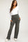 woman wearing a white long sleeve maternity top and grey maternity pants with pockets, smiling and standing confidently