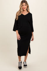 woman wearing a black maternity two-piece outfit with a v-neck top and a midi skirt featuring a side slit