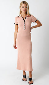 woman wearing a pink ribbed midi dress with a collared neck and black button details