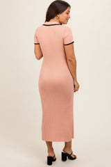 woman wearing a pink ribbed maternity dress with short sleeves and contrasting black trim, fitted silhouette