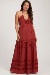 woman wearing a rust red maternity maxi dress with ruffle details and a halter neckline, showcasing her baby bump