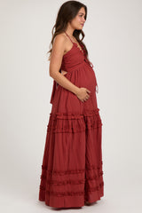woman wearing a rust maternity maxi dress with ruffled details and a baby bump, standing sideways