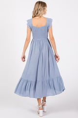 woman wearing a light blue flutter sleeve maxi dress with a smocked bodice and tiered skirt