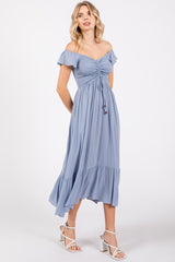 woman wearing a light blue off-the-shoulder maxi dress with ruffle sleeves and a tie detail at the waist
