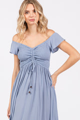 woman wearing a light blue off-the-shoulder dress with smocked bodice and tie detail at the waist