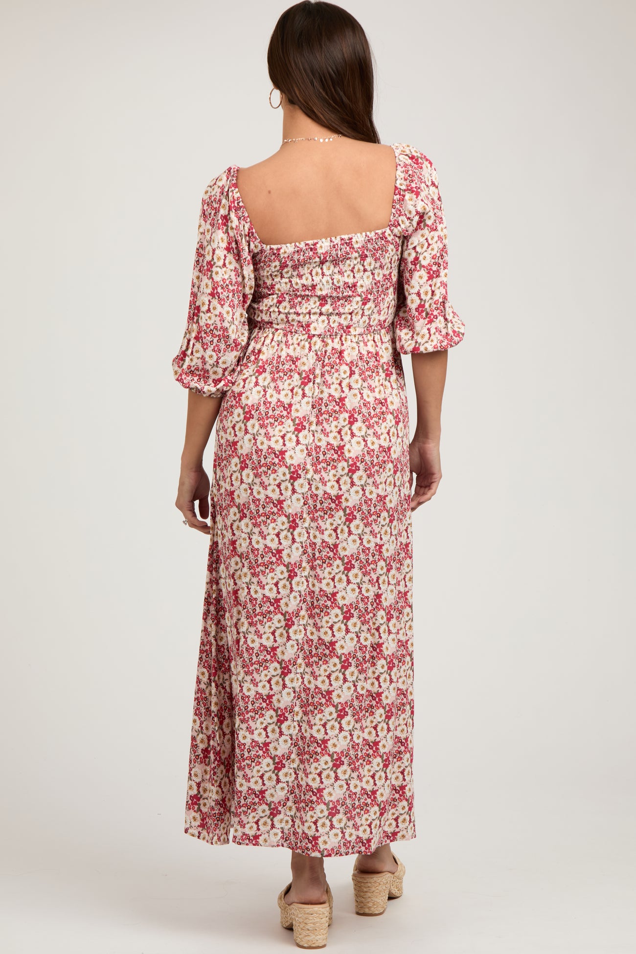 woman wearing a floral maternity maxi dress with puff sleeves and a smocked back, showcasing a baby bump