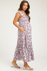 woman wearing a lavender floral maternity maxi dress with ruffle details and pockets, highlighting her baby bump