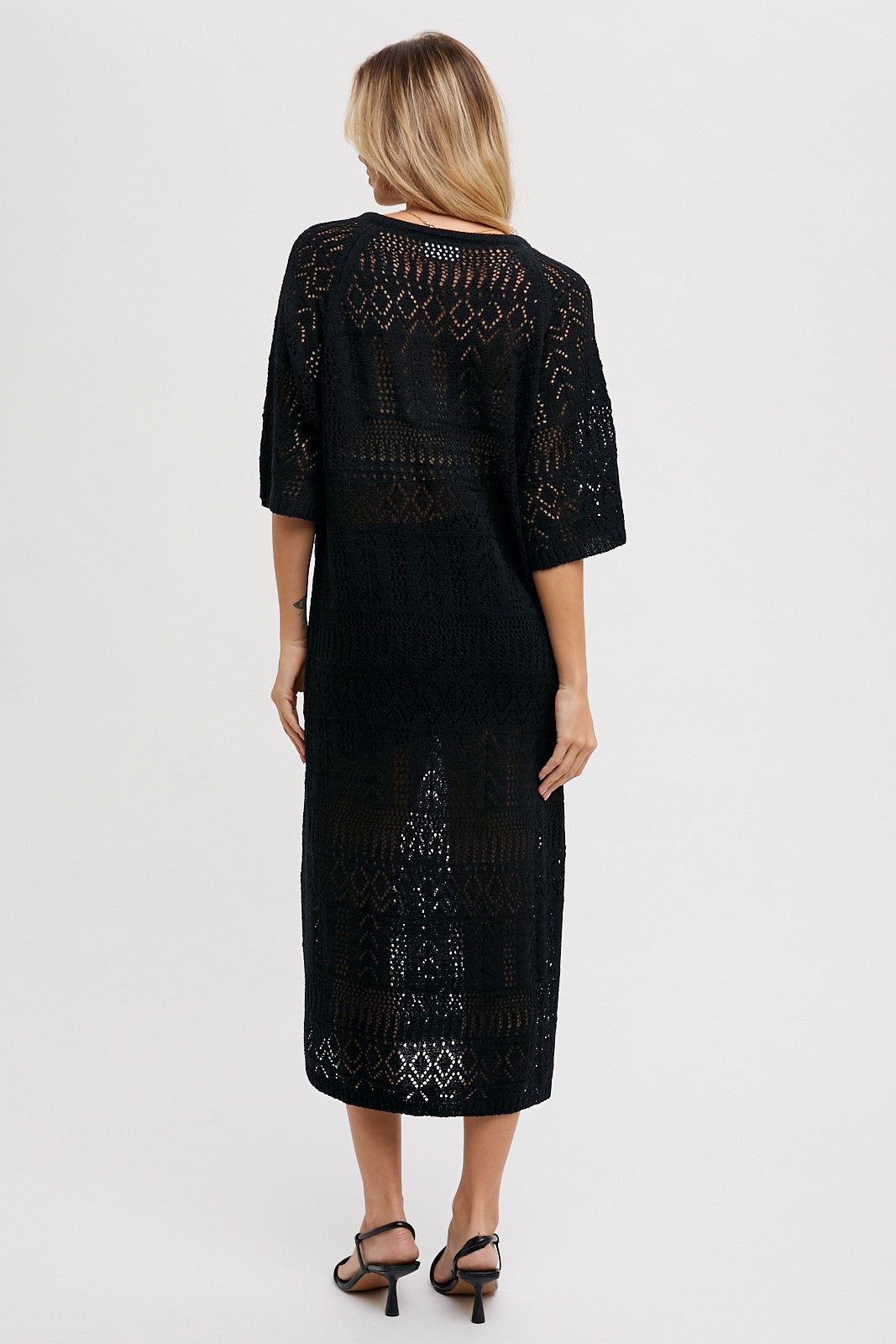 woman wearing a black open-knit maxi dress with short sleeves, shown from the back