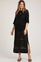 woman wearing a black crochet maternity dress with a tie neck and side slits, showcasing her baby bump