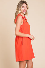 woman wearing an orange sleeveless dress with tie details on the shoulders and a relaxed fit