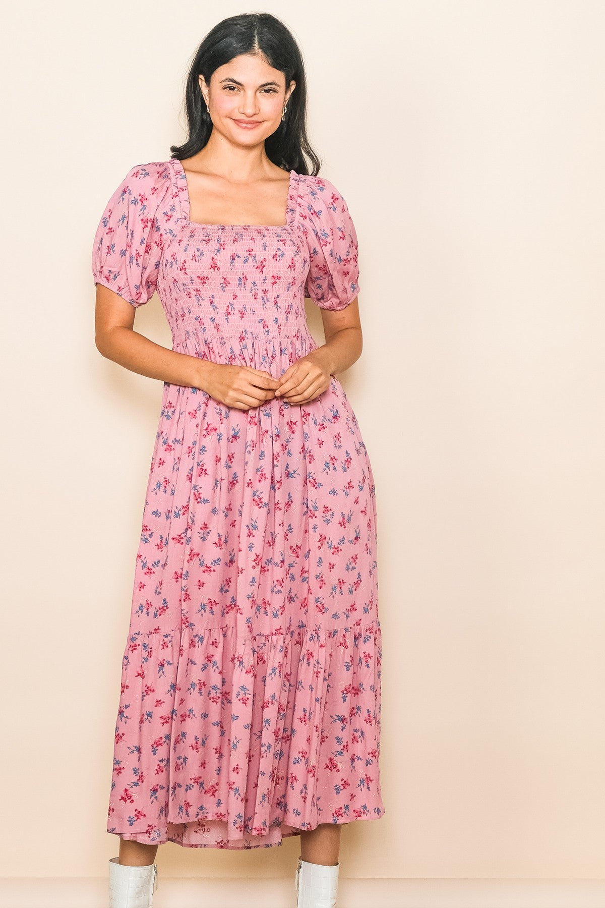 woman wearing a pink floral maxi dress with smocked bodice and puff sleeves, standing against a light background
