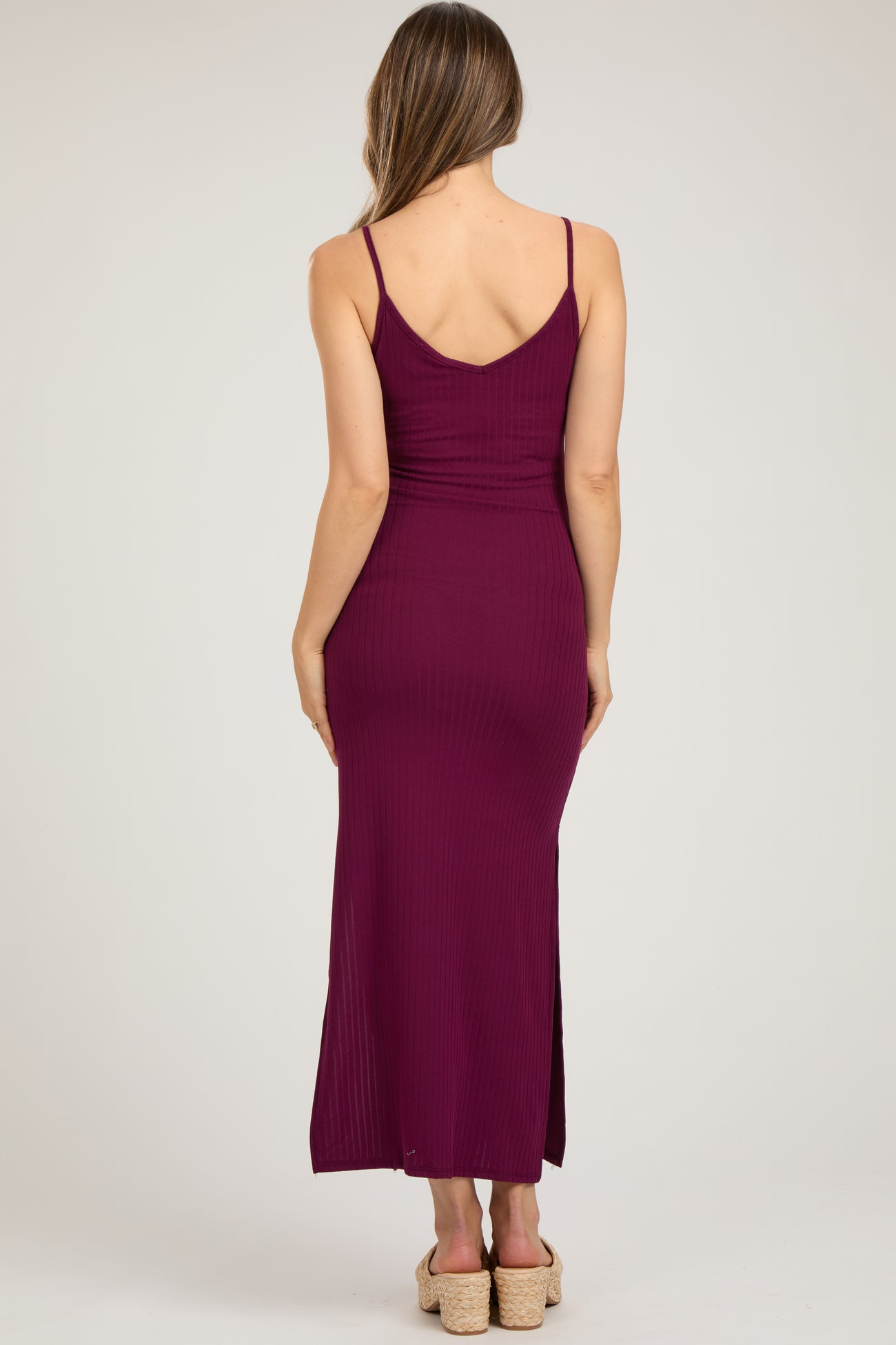 woman wearing a maroon ribbed maternity maxi dress with a fitted silhouette and side slit