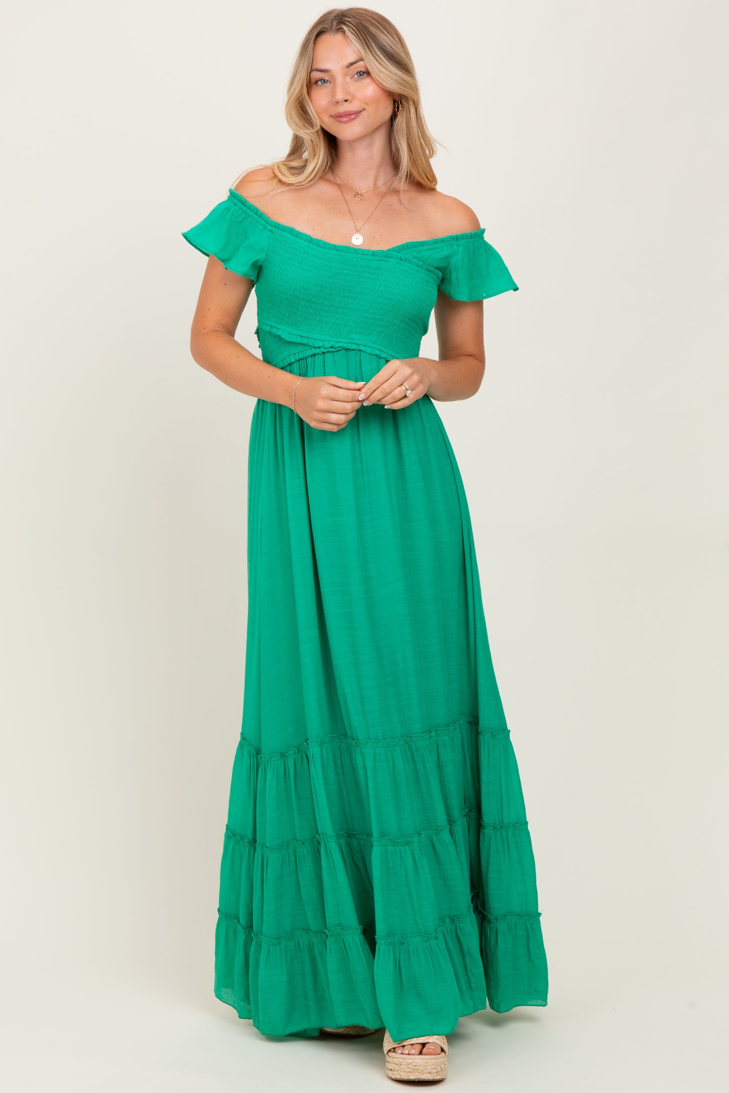 woman wearing a green off-the-shoulder maxi dress with tiered hem and a fitted bodice