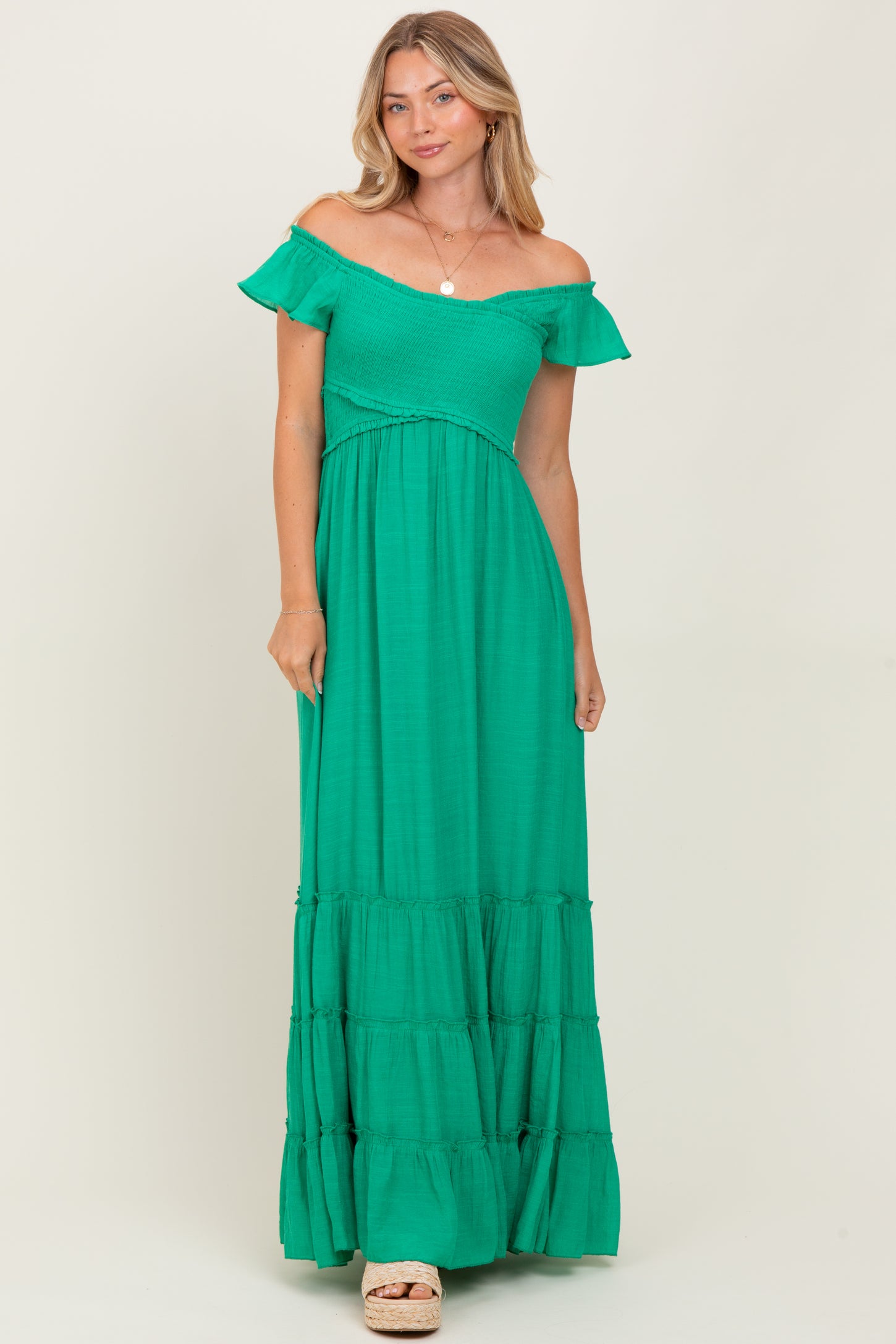woman wearing a green off-the-shoulder maxi dress with tiered skirt and ruffle details