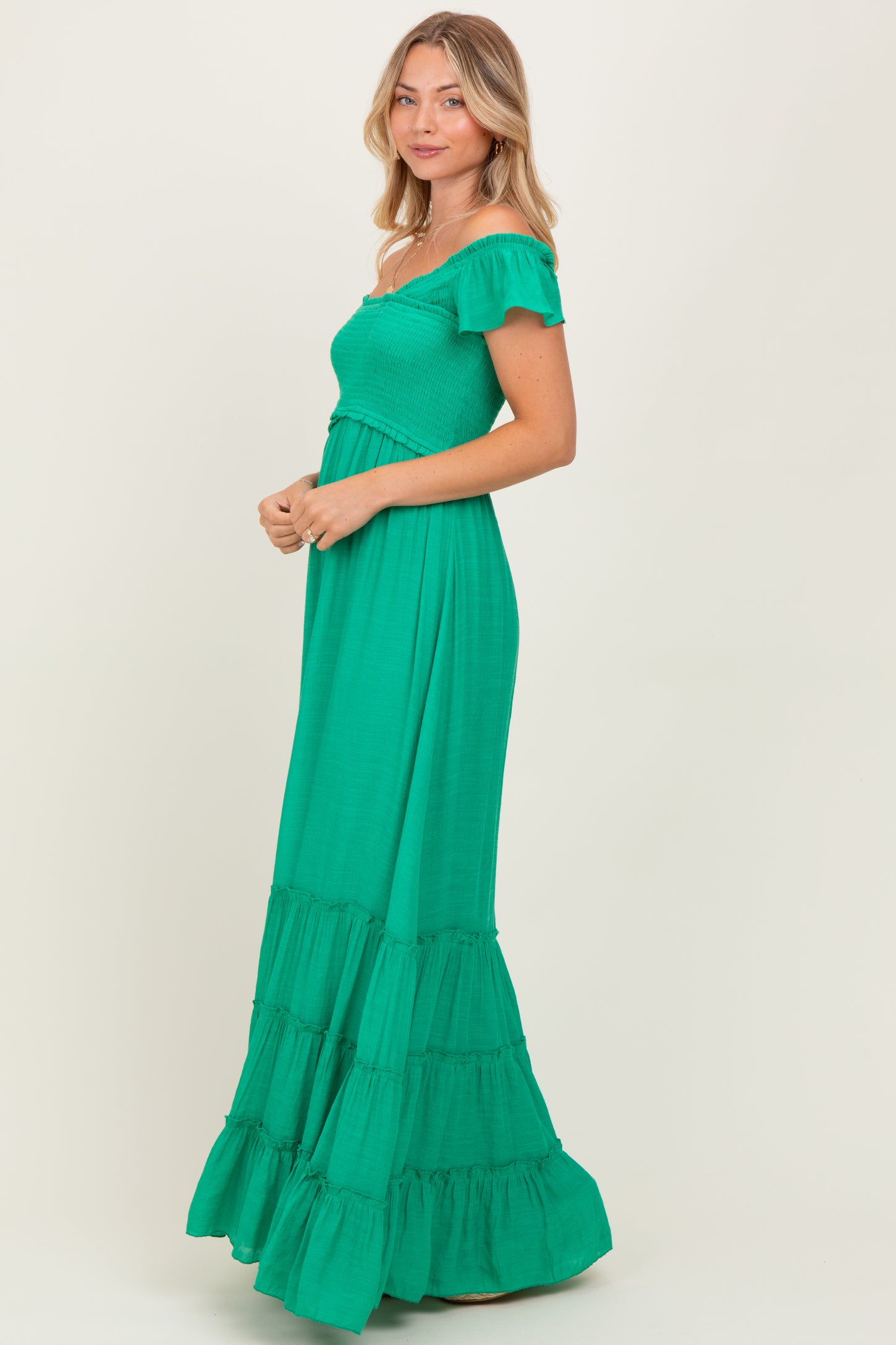 woman wearing a green off-shoulder maxi dress with a smocked bodice and tiered ruffles at the hem