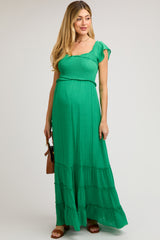 woman wearing a green maternity maxi dress with short flutter sleeves and tiered hem, showcasing her baby bump