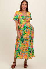 woman wearing a vibrant yellow floral maternity dress with short sleeves and a baby bump visible