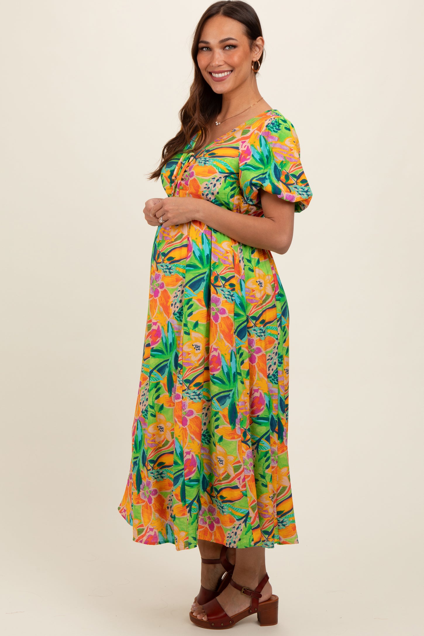 woman wearing a colorful floral maternity dress with short puff sleeves and a baby bump visible