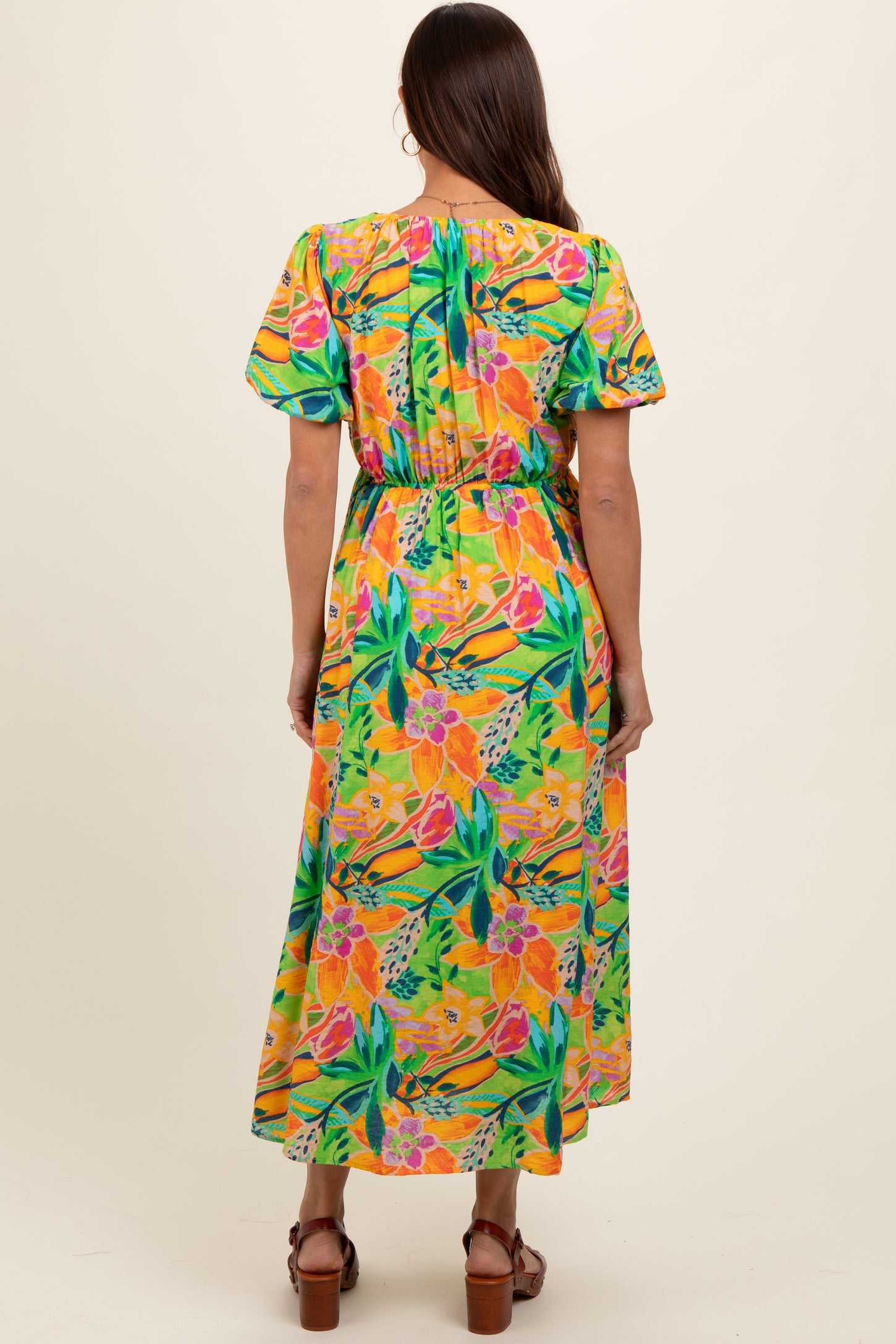 woman wearing a floral maternity maxi dress in vibrant colors, showcasing a flowy fit and short sleeves from the back
