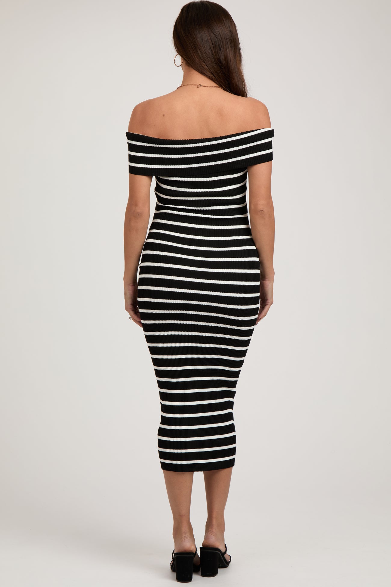 woman wearing a black and white striped off-the-shoulder maternity dress, fitted style, showing her back