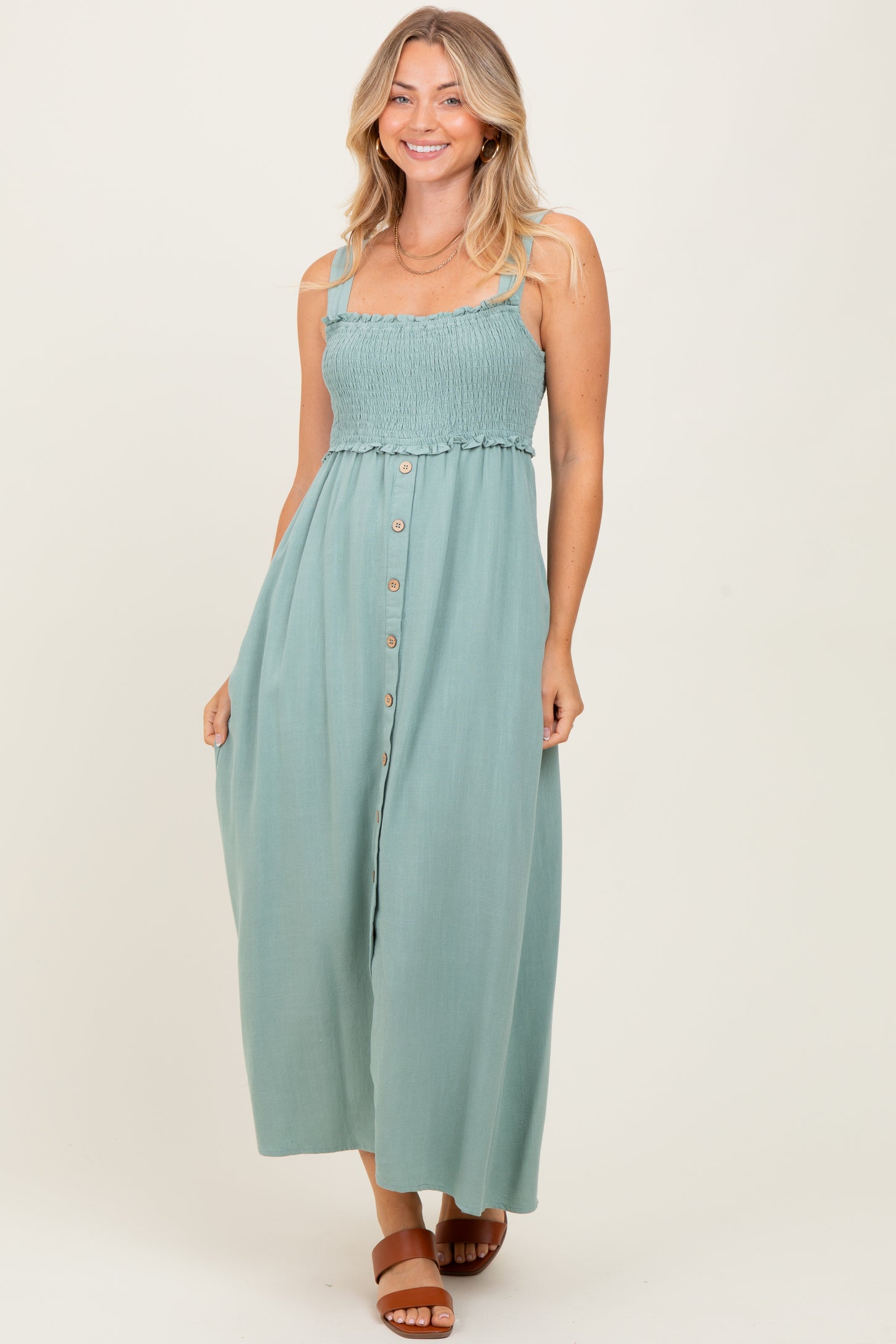 woman wearing a teal smocked bodice maxi dress with button detailing and adjustable straps