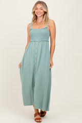 woman wearing a teal smocked bodice maxi dress with button detailing and adjustable straps