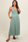 woman wearing a teal maternity maxi dress with smocked bodice and button-down front, posing with one hand on her hip