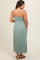 woman wearing a sage green maternity maxi dress with a smocked bodice and adjustable straps from the back