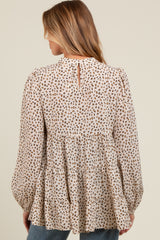 woman wearing a beige maternity top with a brown animal print and tiered ruffle design, showing a keyhole back detail