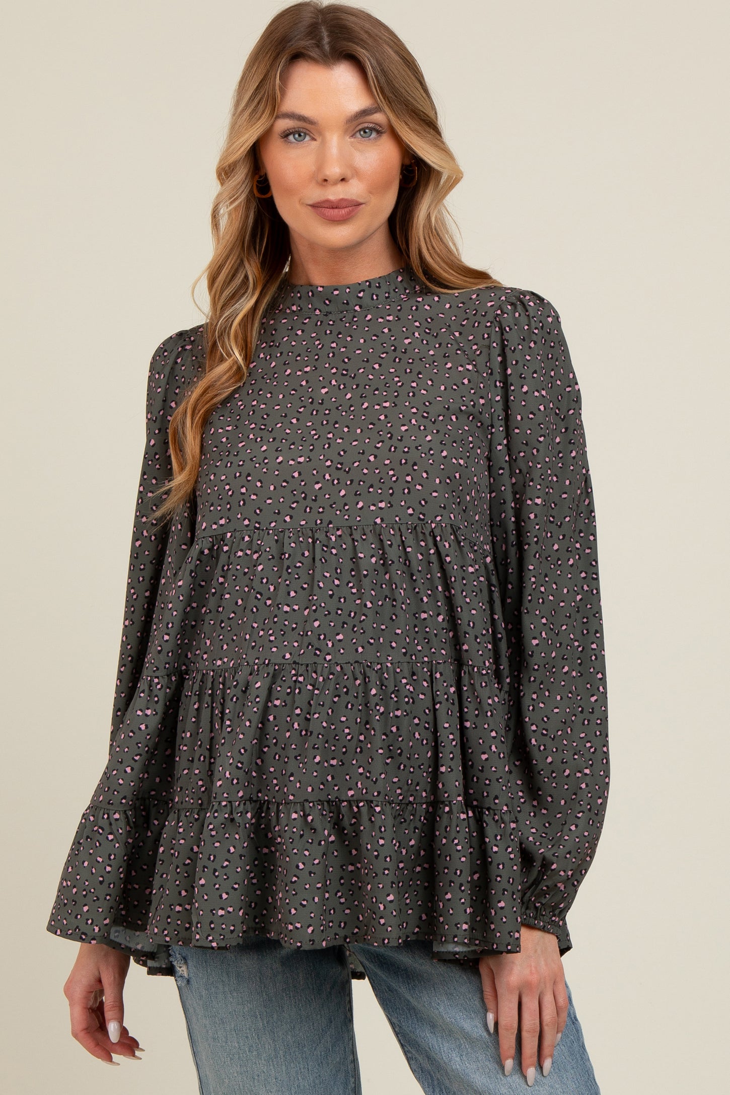 woman wearing a dark grey puff sleeve maternity blouse with pink and purple spots and tiered ruffle hem