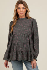 woman wearing a dark grey puff sleeve maternity blouse with pink and purple spots and tiered ruffle hem