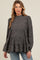 woman wearing a dark grey puff sleeve maternity blouse with pink and purple spots and tiered ruffle hem