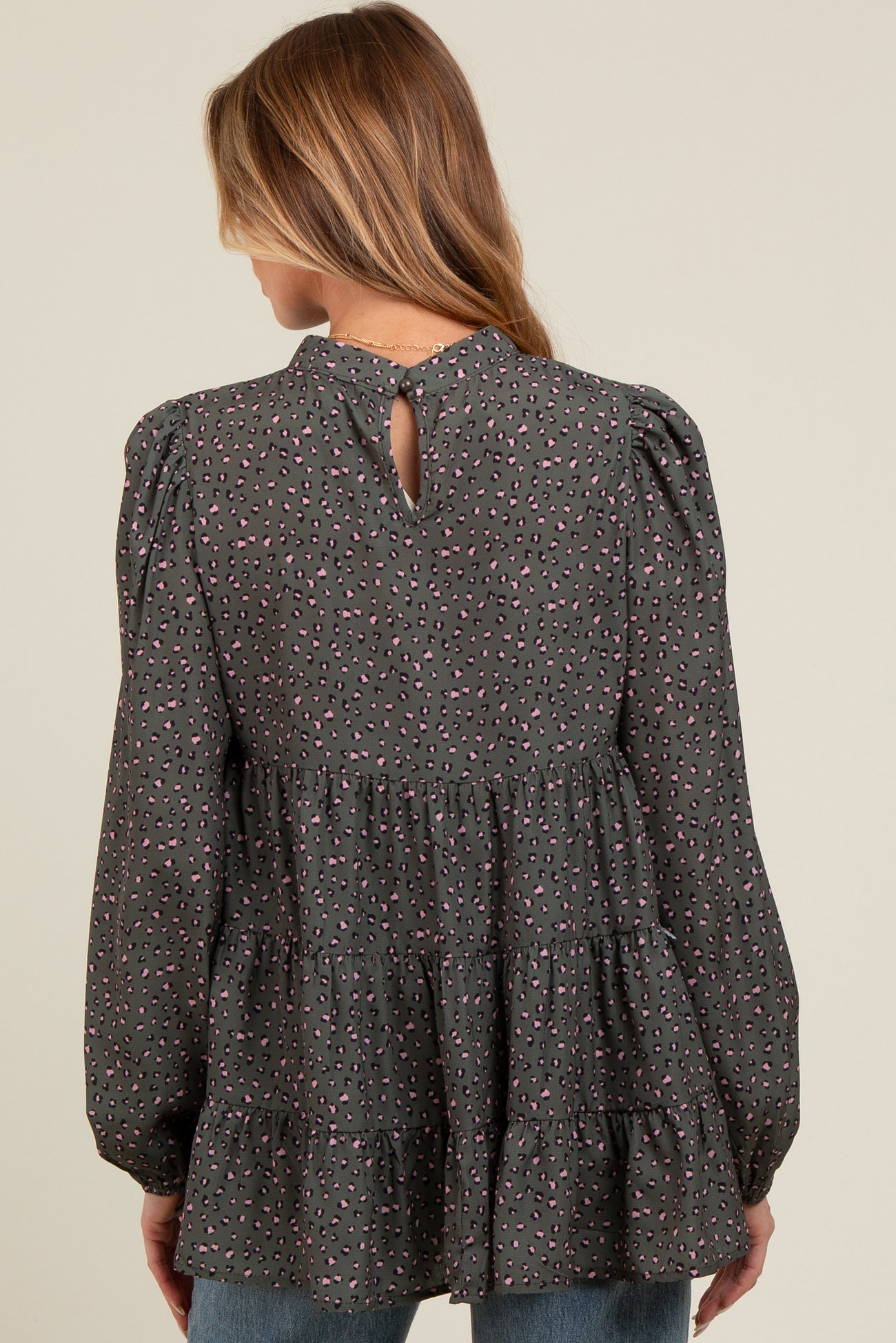 woman wearing a dark gray maternity top with a tiered design and colorful print, showing a keyhole detail at the back