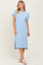 woman wearing a light blue relaxed fit ribbed midi dress with rolled sleeves and side slits