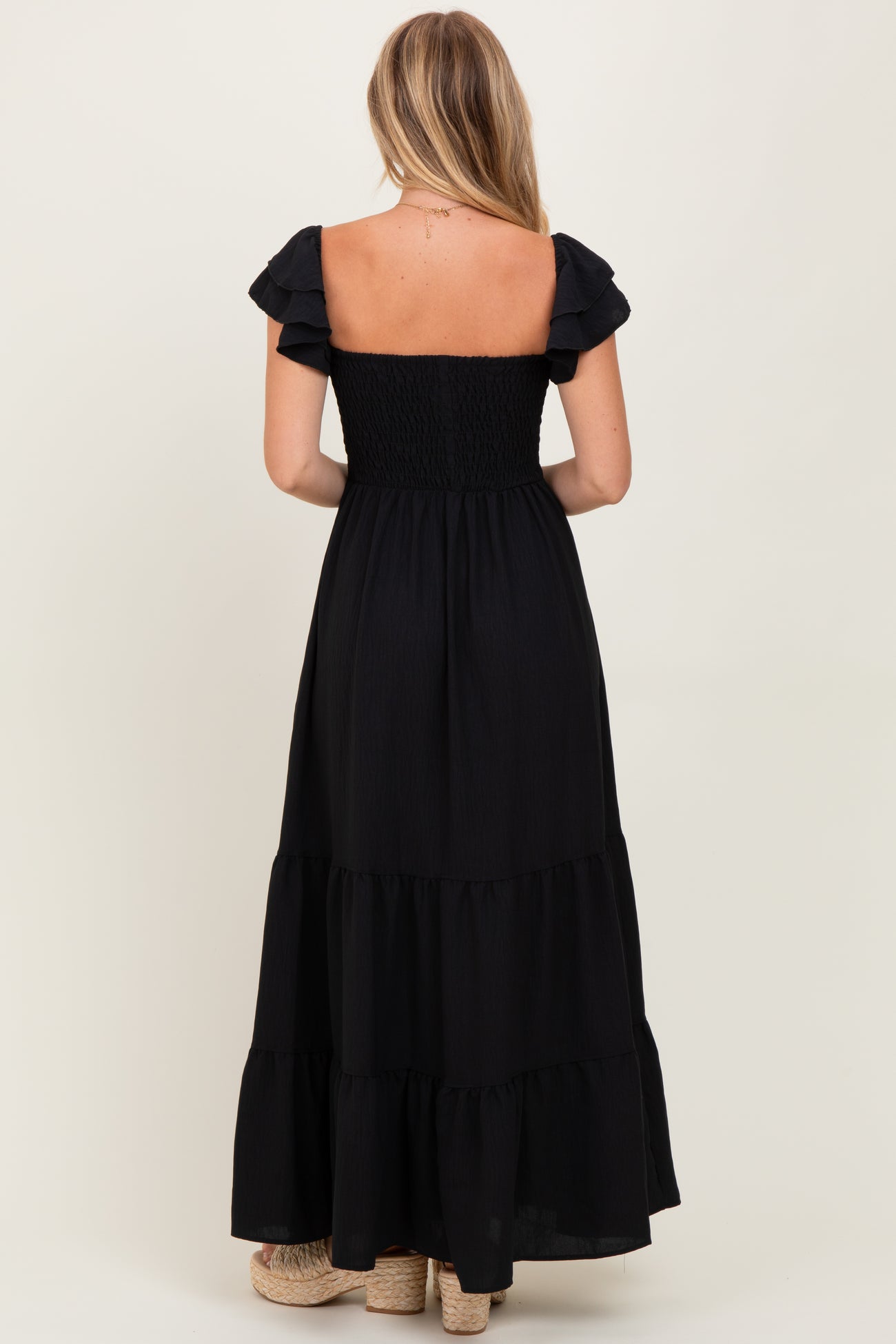 woman wearing a black off-the-shoulder maxi dress with puff sleeves and tiered skirt from the back