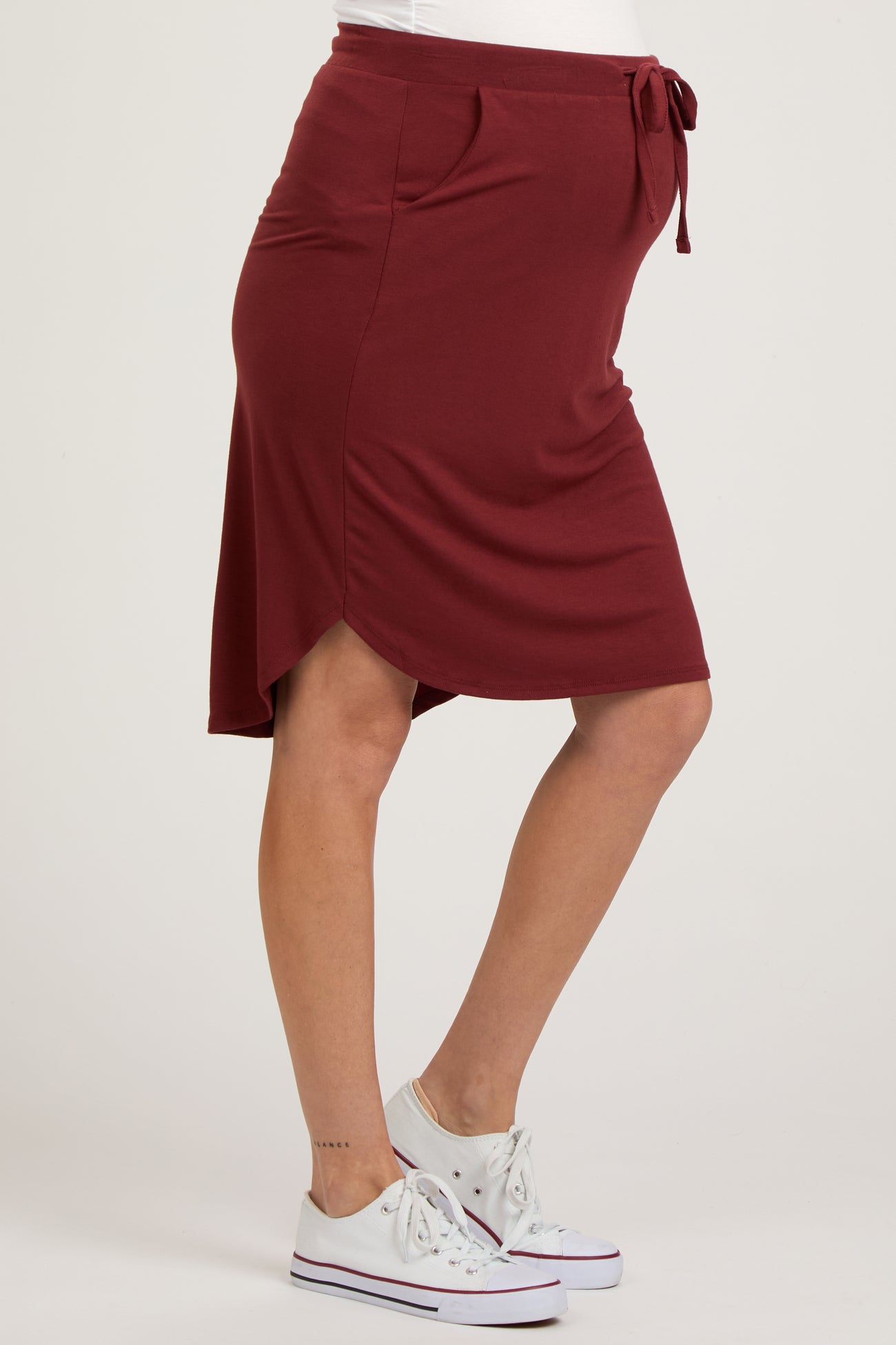 maternity wear burgundy knee-length skirt with drawstring waist and side pockets, model showing baby bump