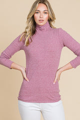 woman wearing a lavender long sleeve turtleneck top paired with white pants