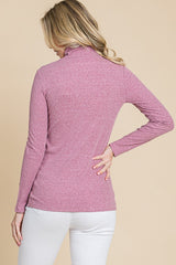 woman wearing a light pink long sleeve turtleneck top, viewed from the back