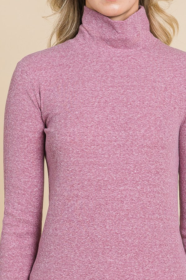 woman wearing a pink ribbed turtleneck sweater with long sleeves