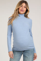 woman wearing a light blue long sleeve maternity top with a mock neck and visible baby bump
