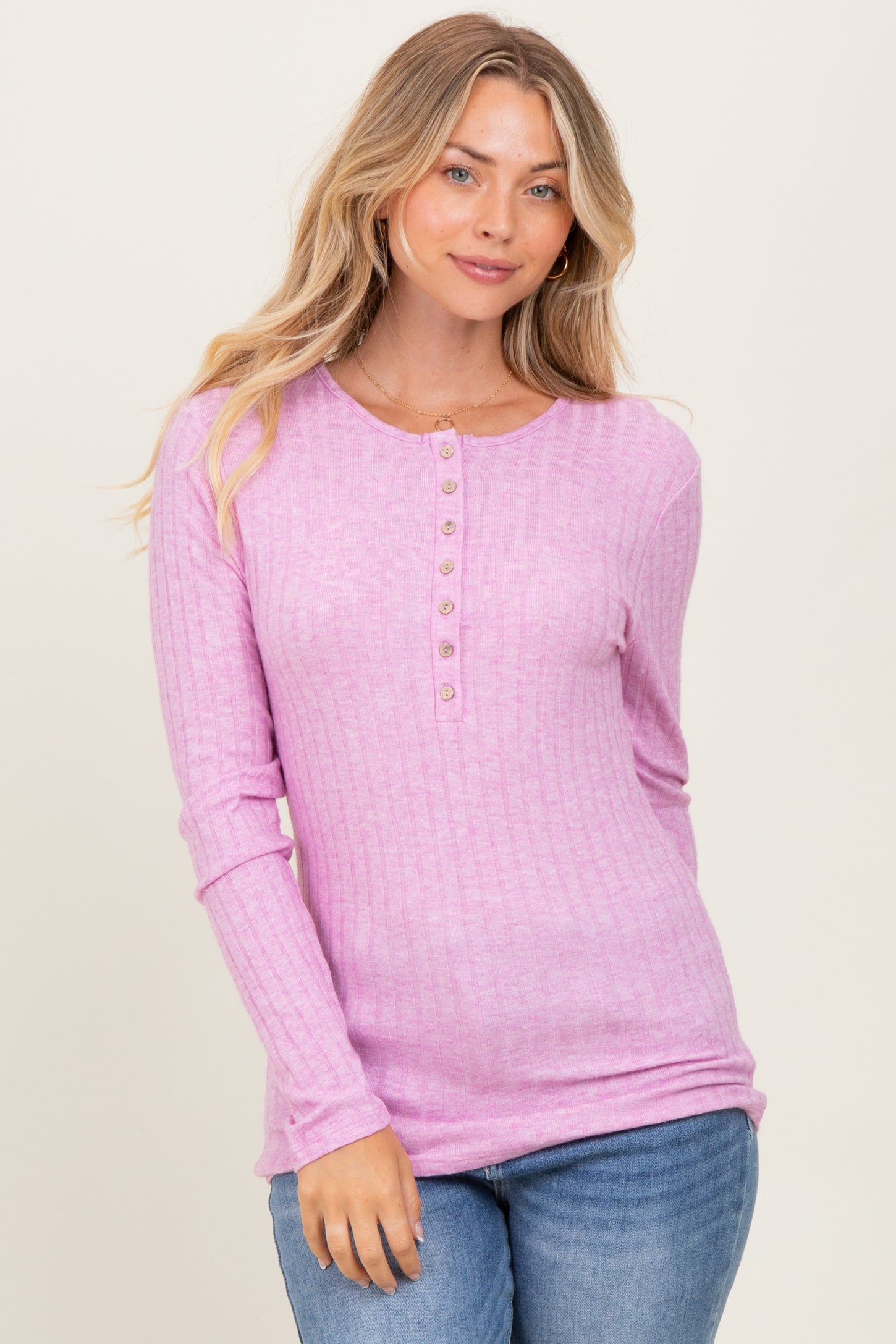 woman wearing a light pink ribbed long sleeve top with buttons and a relaxed fit