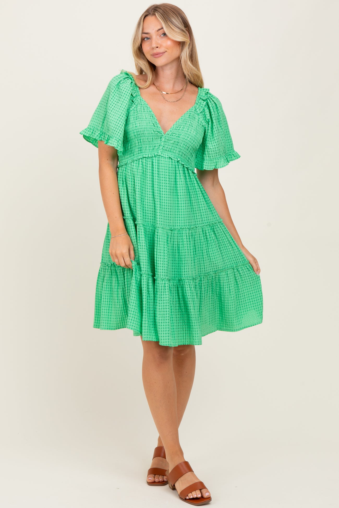 woman wearing a green gingham tiered dress with puff sleeves and a v-neckline