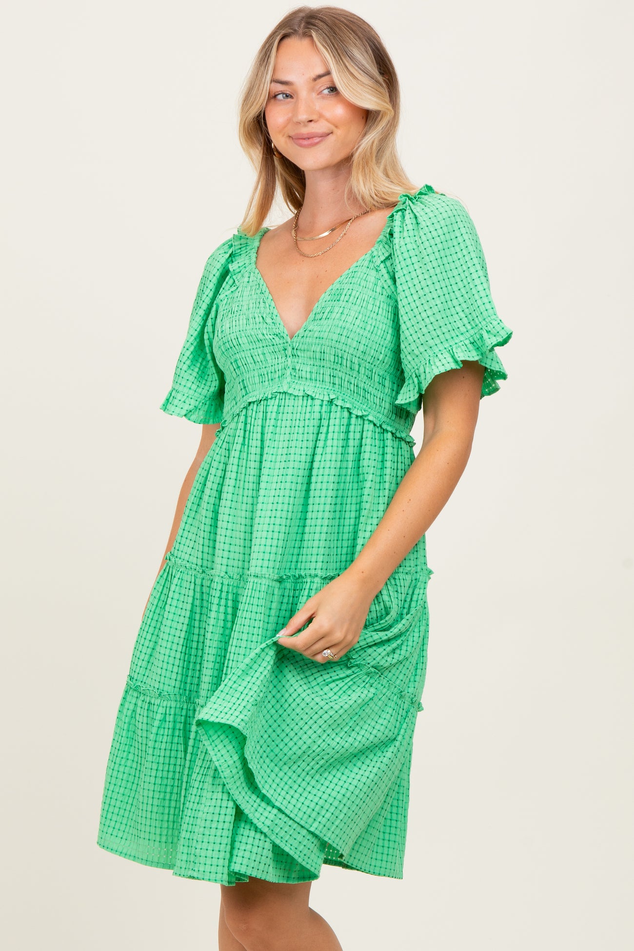 woman wearing a green checkered tiered dress with short puff sleeves and a v-neckline