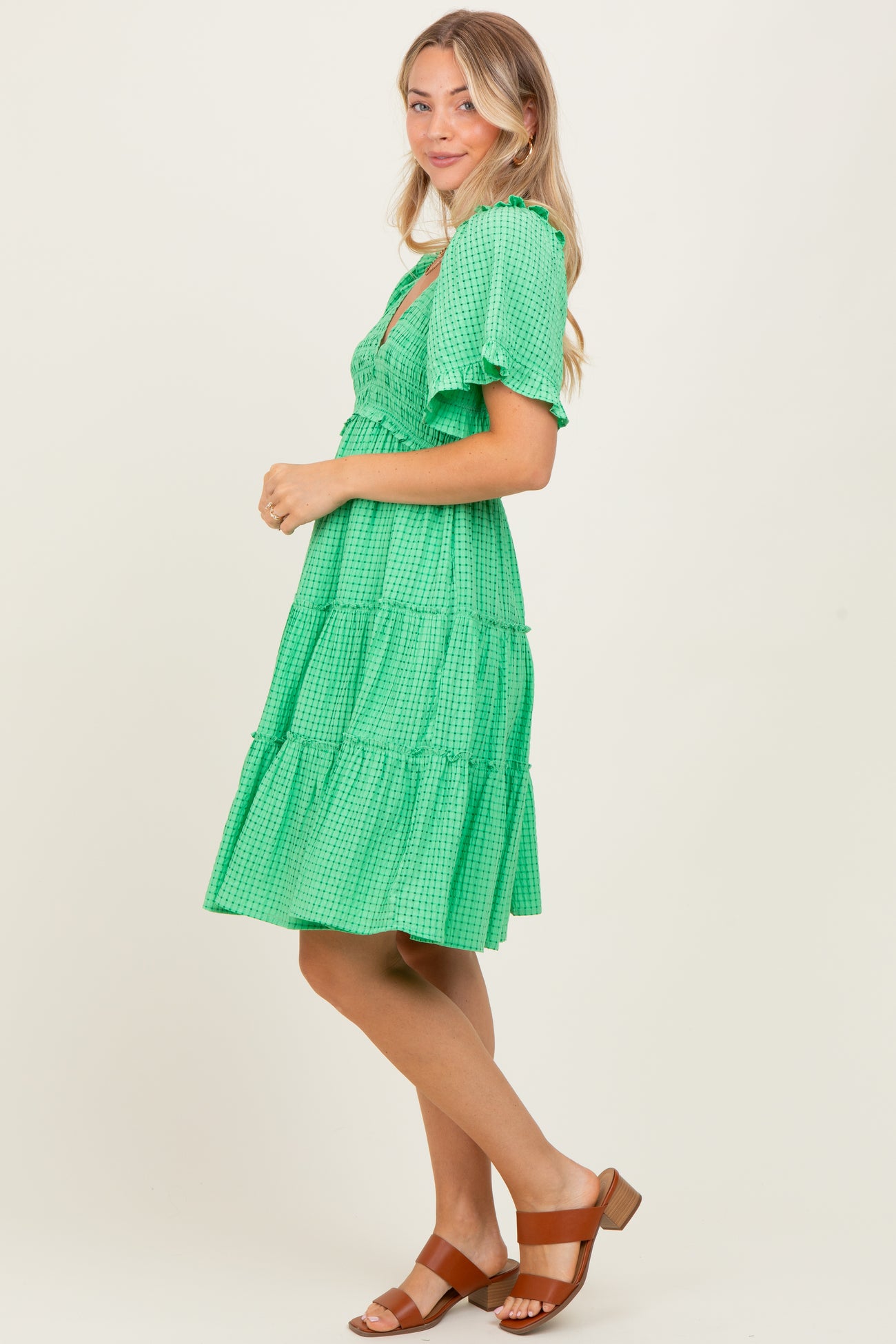 woman wearing a green tiered midi dress with short sleeves and a ruffled neckline