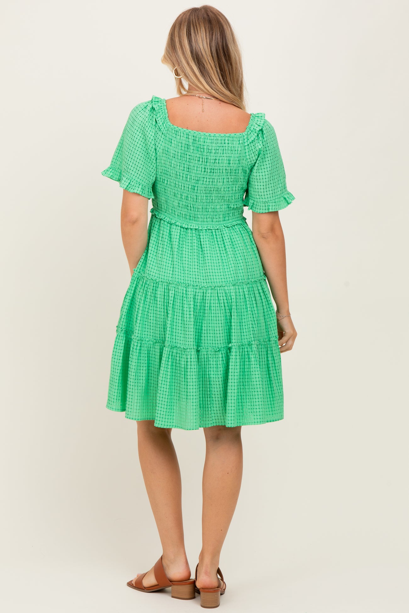 woman wearing a green tiered dress with short sleeves and smocked bodice seen from the back