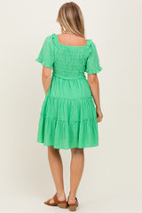 woman wearing a green tiered dress with short sleeves and smocked bodice seen from the back