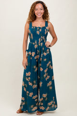 woman wearing a teal floral maxi jumpsuit with smocked bodice and wide-leg bottoms