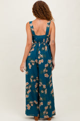 woman wearing a teal floral maxi dress with a smocked back and wide leg pants, standing with her back to the camera