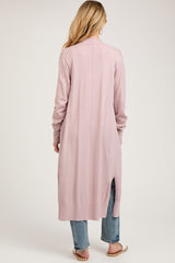 woman wearing a dusty pink long sleeve maternity cardigan with side slits and paired with jeans