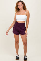 woman wearing a white crop top and purple elastic waist shorts with a relaxed fit
